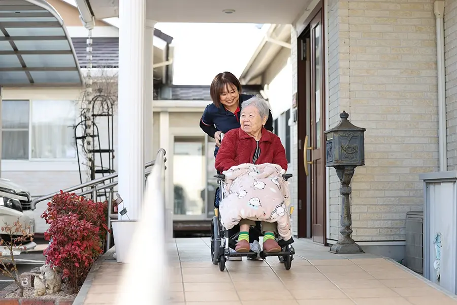 訪問看護スタッフと車椅子に乗る利用者の散歩風景